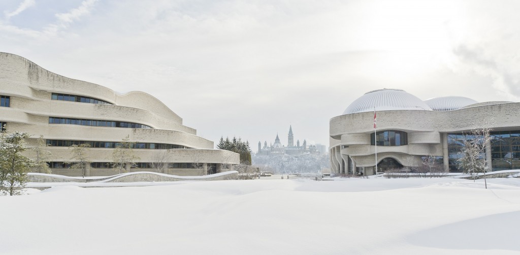 Photographie du Musée canadien de l’histoire et du pavillon administratif en hiver, avec les édifices du Parlement en arrière-plan.