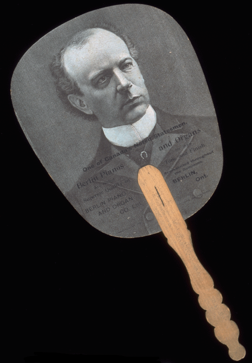 Paper fan with a wooden handle and black-and-white photograph of Sir Wilfrid Laurier. Canadian Museum of History, 1999.124.24