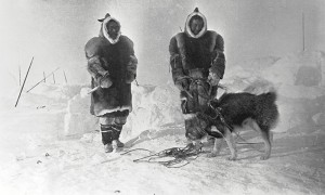 A picture of two Inuit and a dog