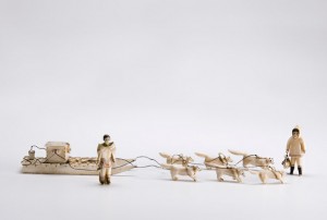 A sculpture of a sled pulled by dogs made out of ivory