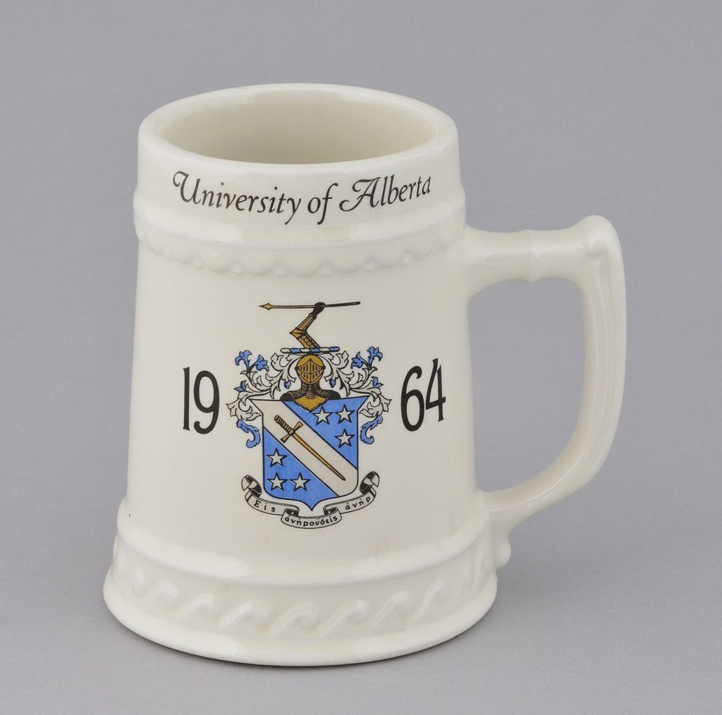 White tankard with a coat of arms, 1964 and "University of Alberta" printed on it.