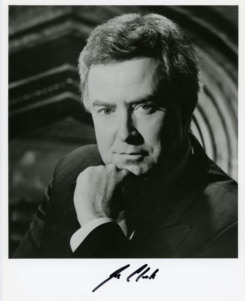 Black and white image of Joe Clark in a suit, with his chin resting on his hand.