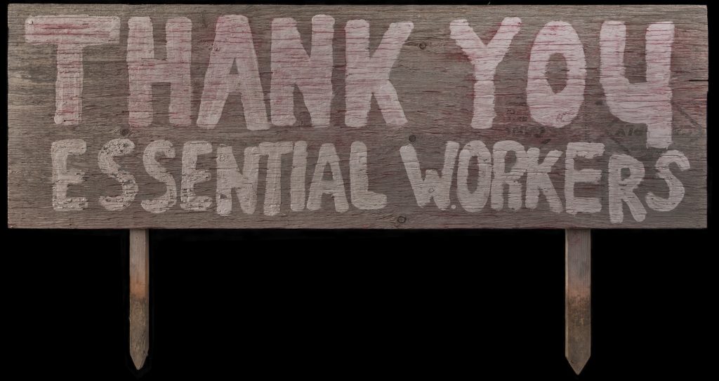 A hand-painted wooden sign reading “Thank You Essential Workers.”