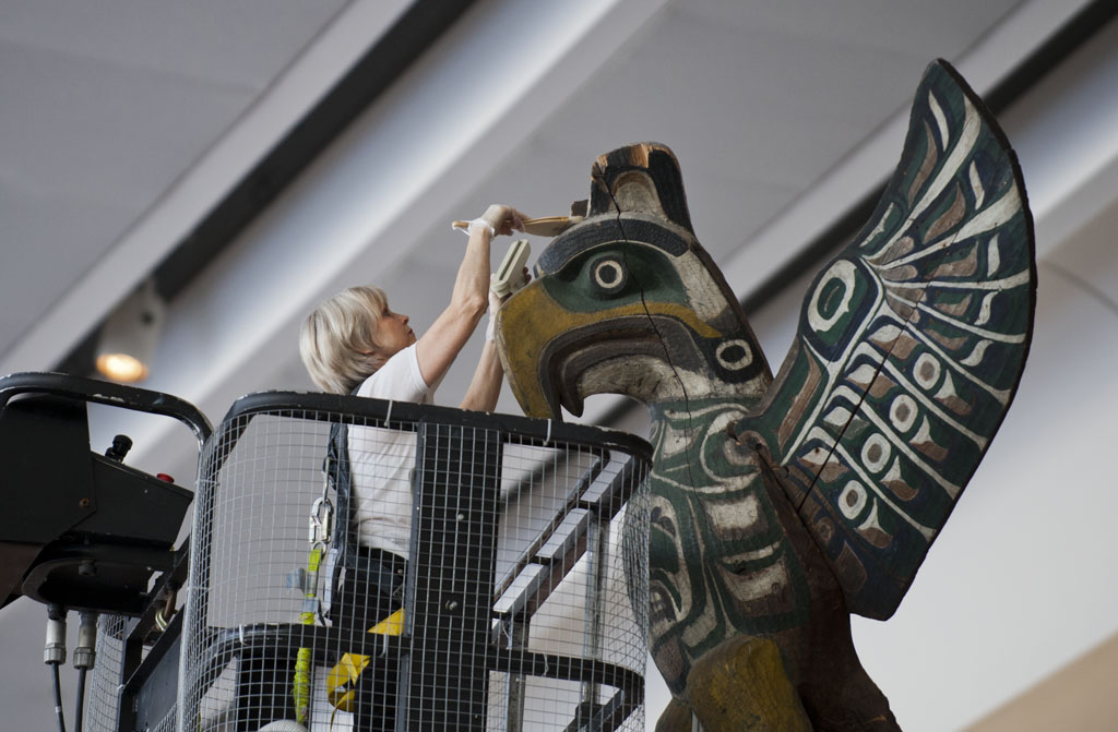 A woman is working on a large eagle sculpture in an airport history hall article.