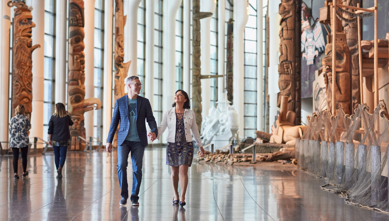 A couple exploring the Canadian Museum of History in Ottawa, admiring the large wooden sculptures.