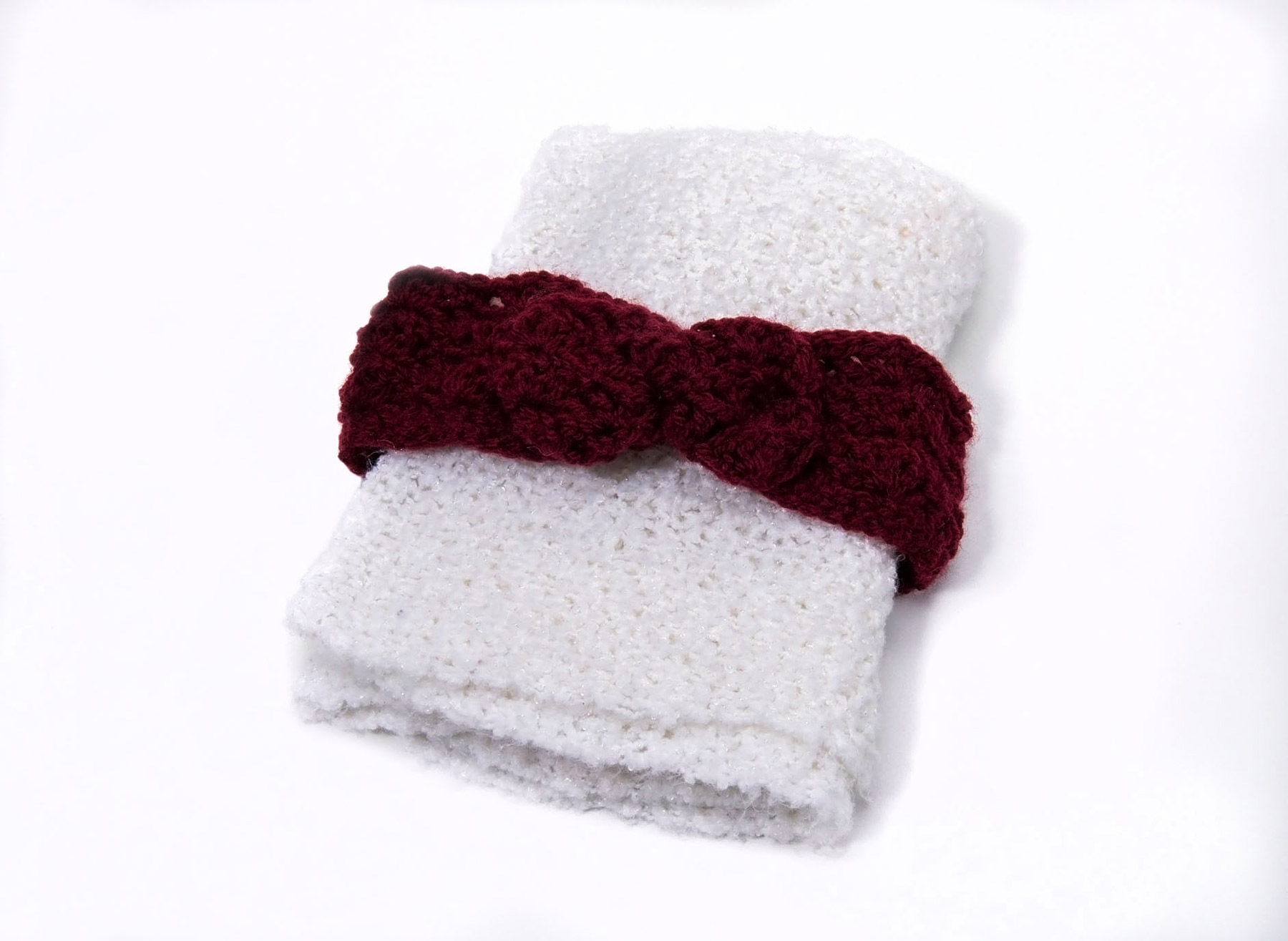 A white and burgundy crocheted headband on a white surface at the Canadian Museum of History.