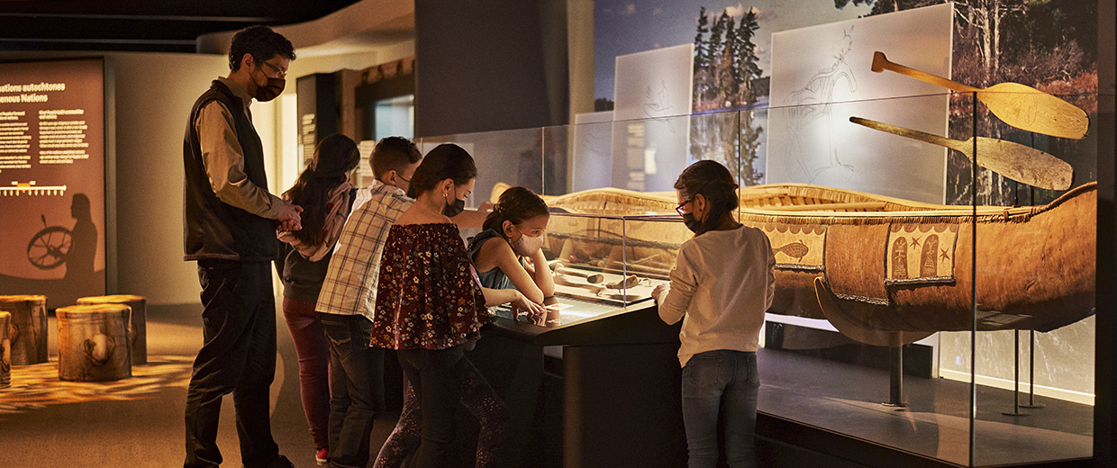 A group of people at the Canadian Museum of History in Ottawa, looking at a display of canoes.