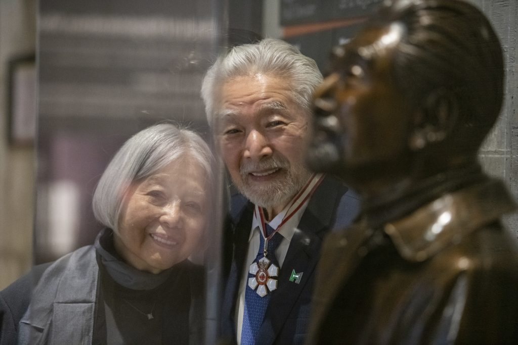 Mr. and Mrs. Moriyama looking at a a bronze statue of Raymond Moriyama. 