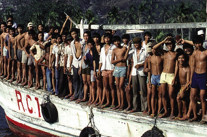 A group of men standing on the back of a boat, experiencing the freedom of open waters as their hearts soar with excitement.