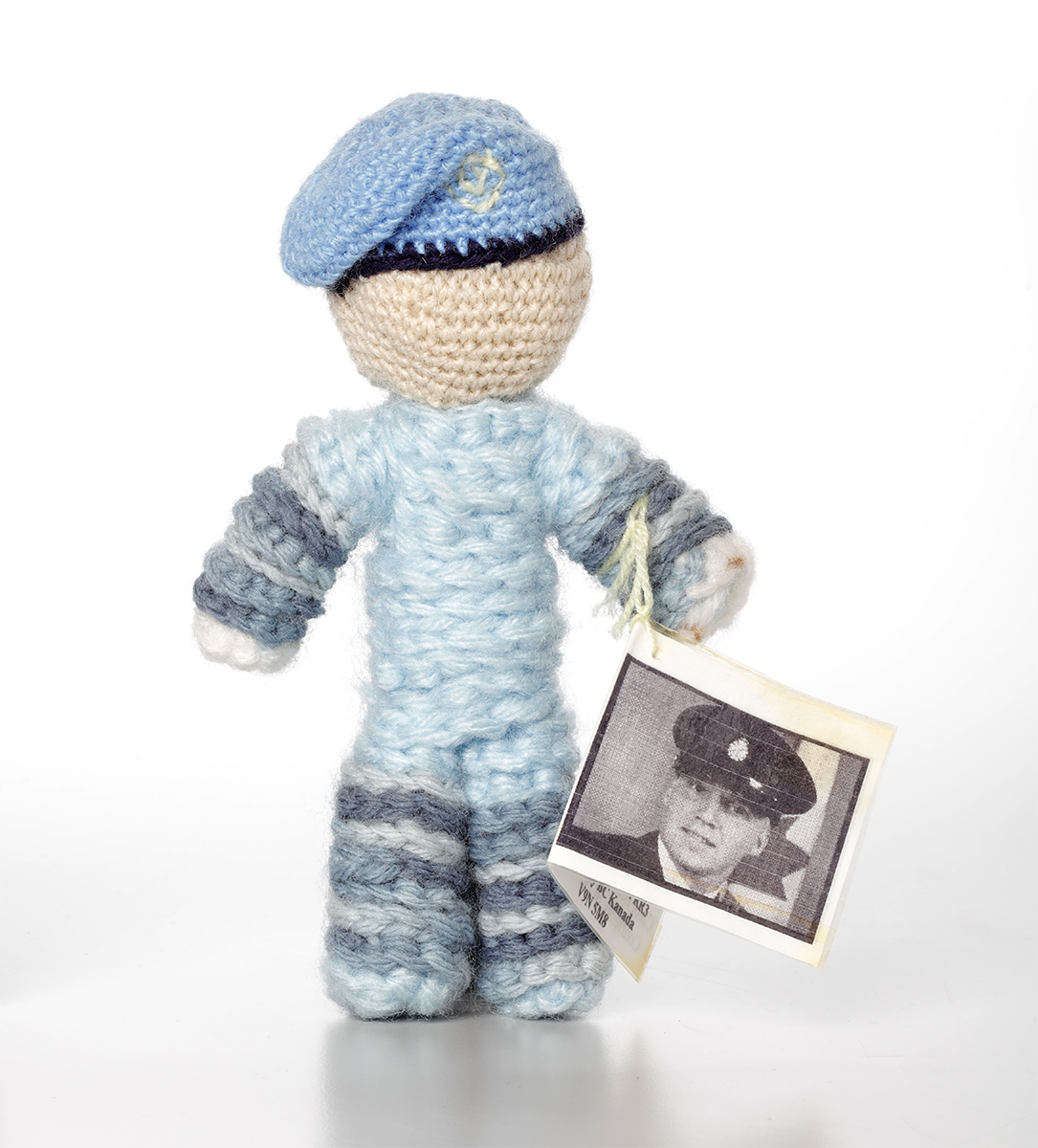 A crocheted doll with a photo wearing a blue hat, displayed at the Canadian Museum of History in Ottawa.