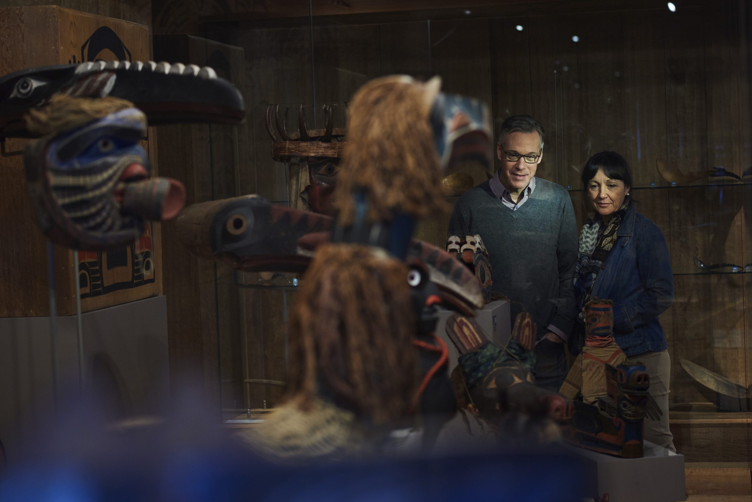 A man and woman stand in front of a display of masks at the Canadian Museum of History in Ottawa.