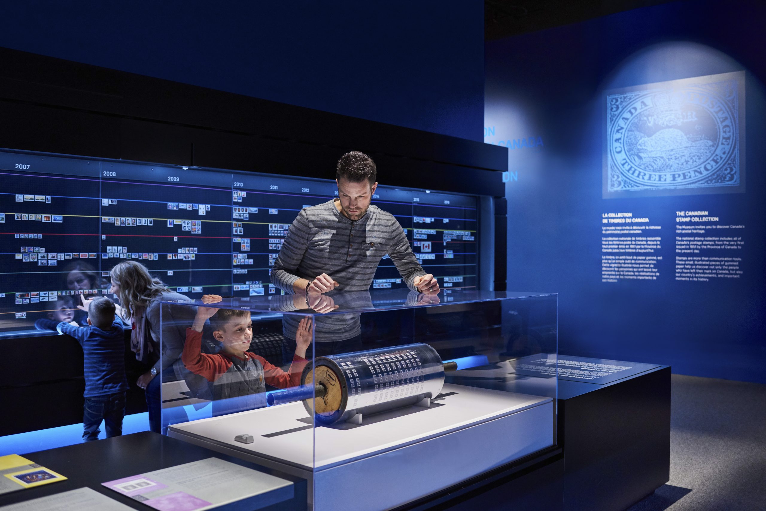 A group of people in Ottawa looking at a display of a stamp book in the Canadian Museum of History.