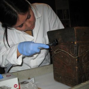 A woman in a lab coat working on a wooden box at the Canadian Museum of History in Ottawa.