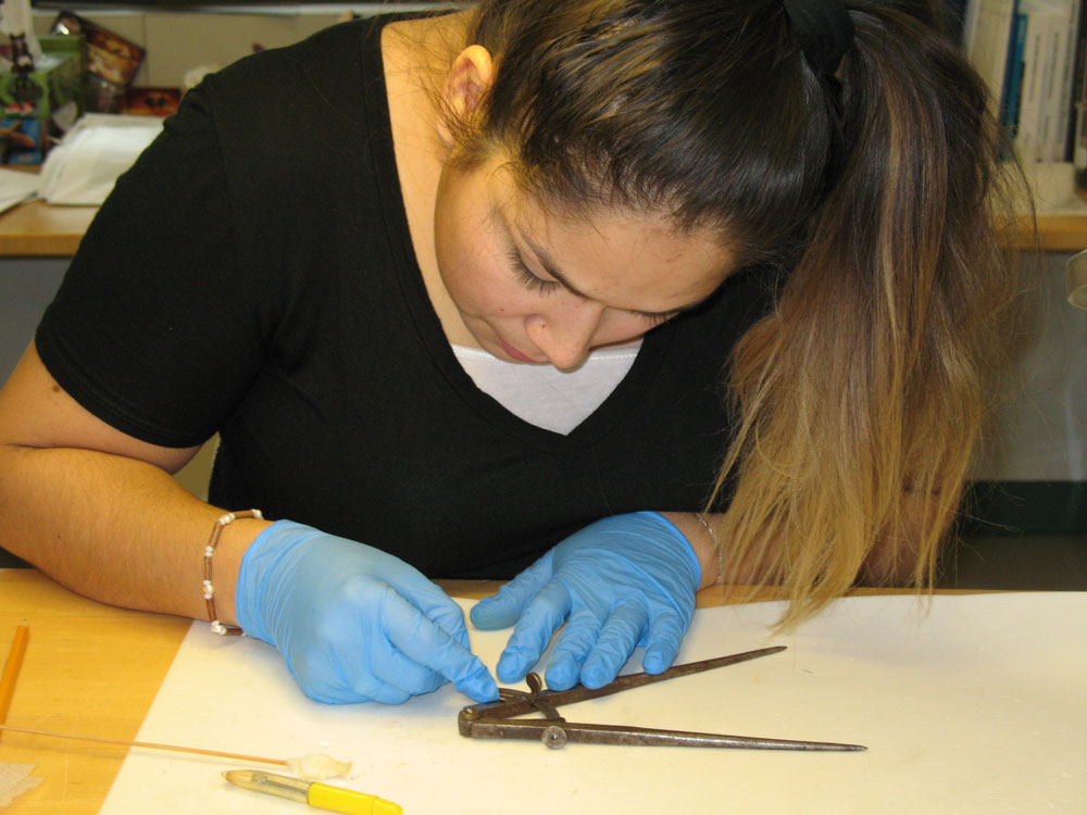 A woman wearing a black shirt reviewing an artifact.