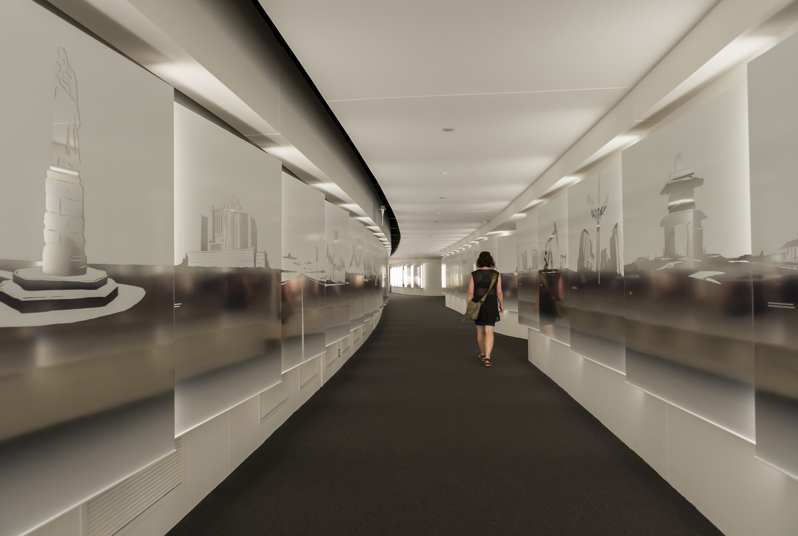 A woman is walking down a hallway with pictures on the wall at the Canadian Museum of History in Ottawa.