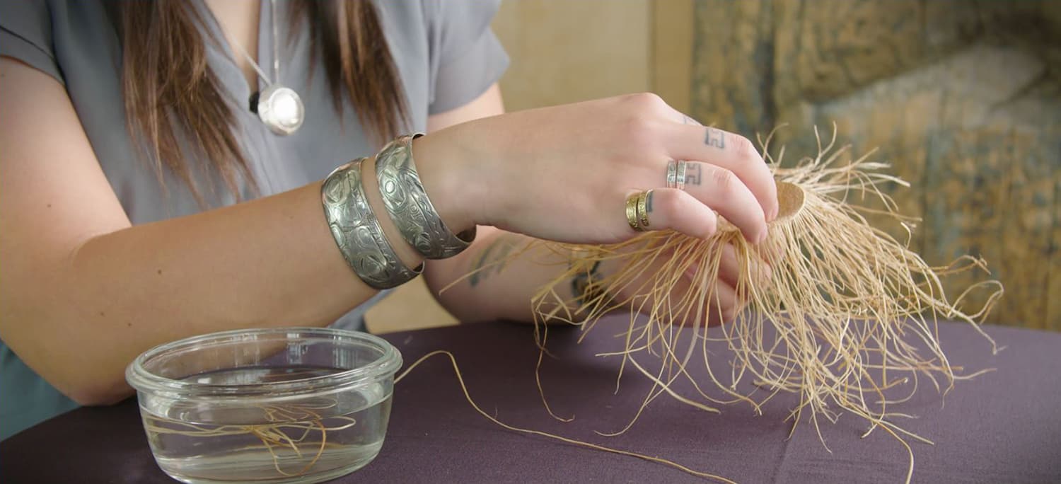 In the Canadian Museum of History in Ottawa, a woman is holding a piece of grass in front of a glass.