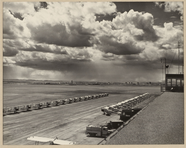 Black and white photo of rows of dozens of airplanes on a tarmac with a cloudy sky