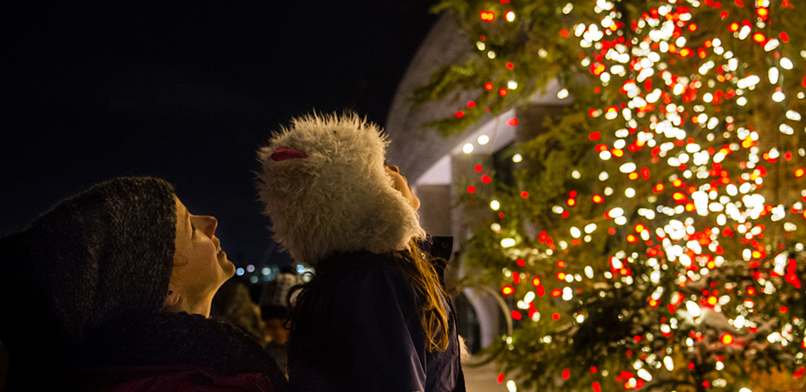 A woman and a child looking up at the Christmas tree