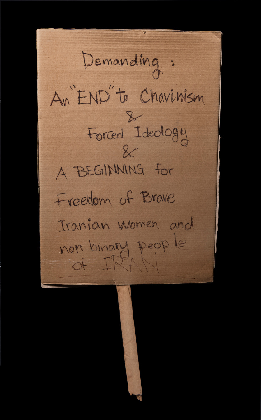 A protest sign reading “Demanding an ‘end’ to Chavinism and forced Ideology and a beginning for freedom of brave Iranian women and nonbinary people of Iran”