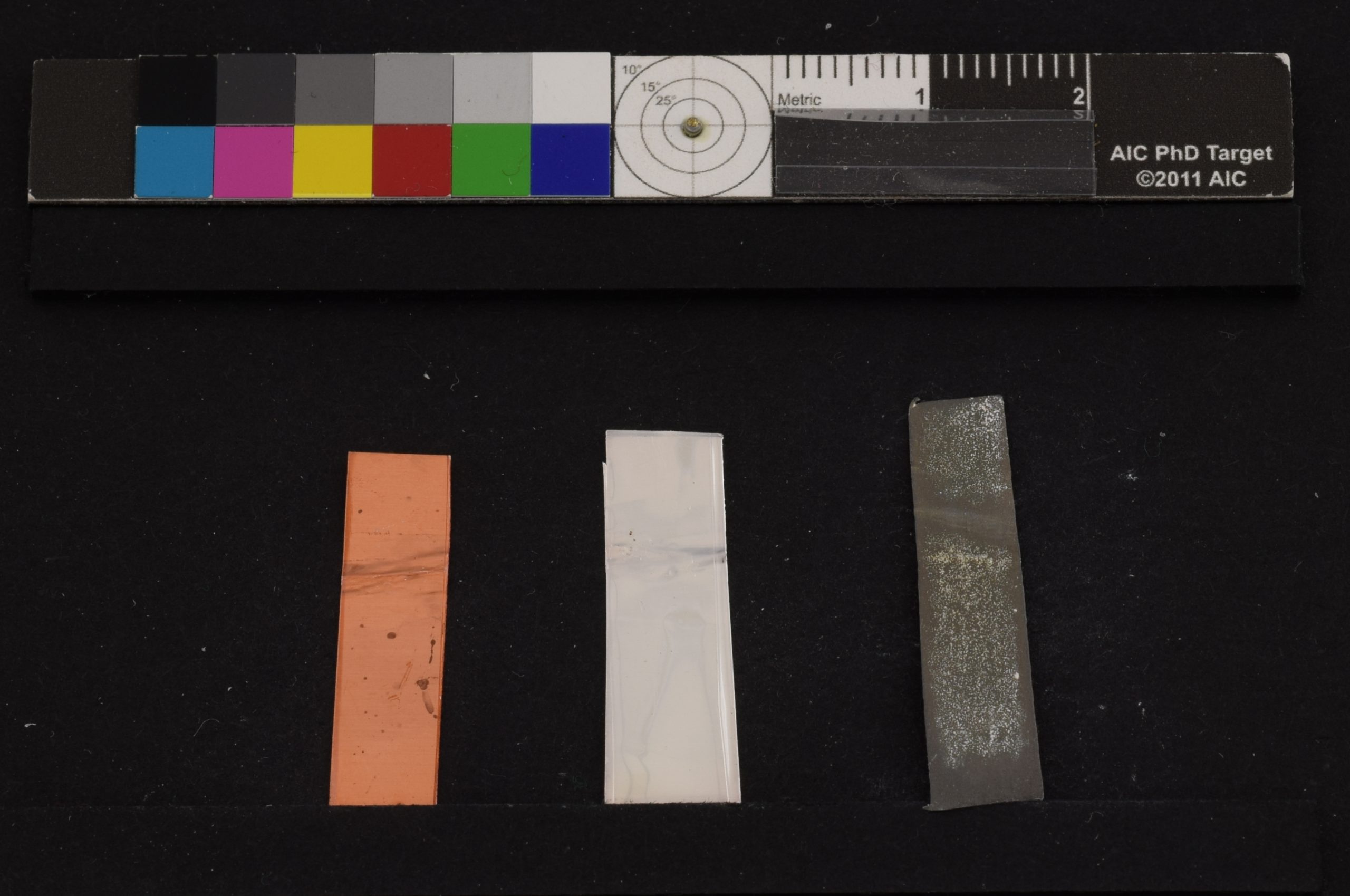 Three rectangular strips (copper, white, and dark grey) with irregular patches of discoloration.