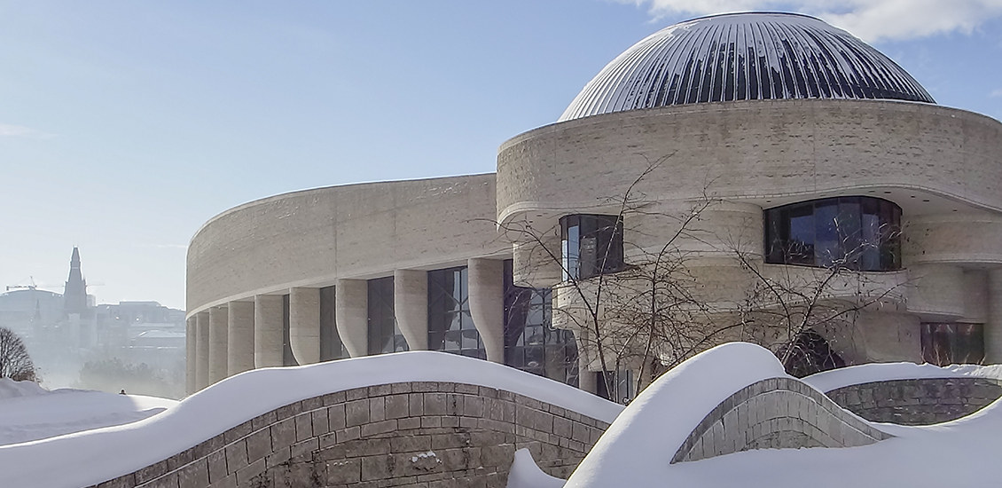 Snowy scene of a stone building with rounded architecture