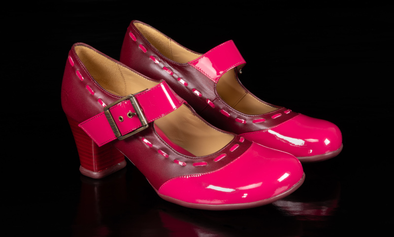 A pair of brown and pink pump shoes with a buckle strap closure and chunky stacked heels.