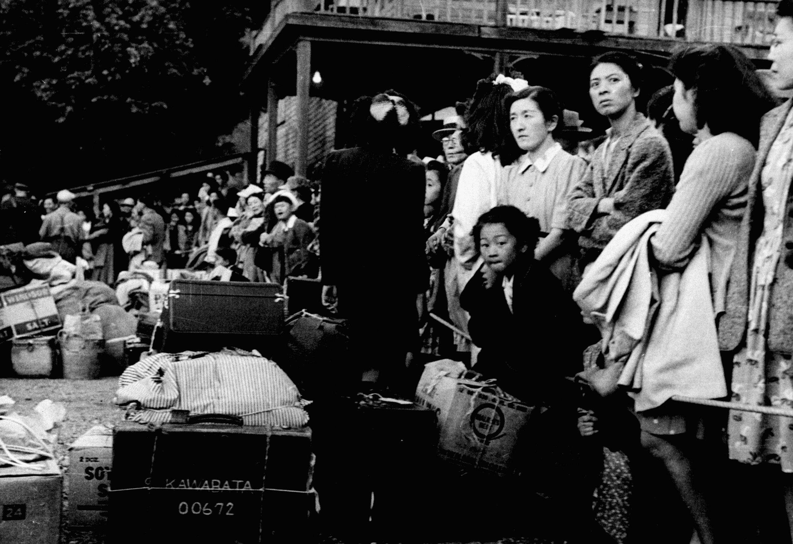 Black-and-white photograph of Japanese Canadians waiting for a train.