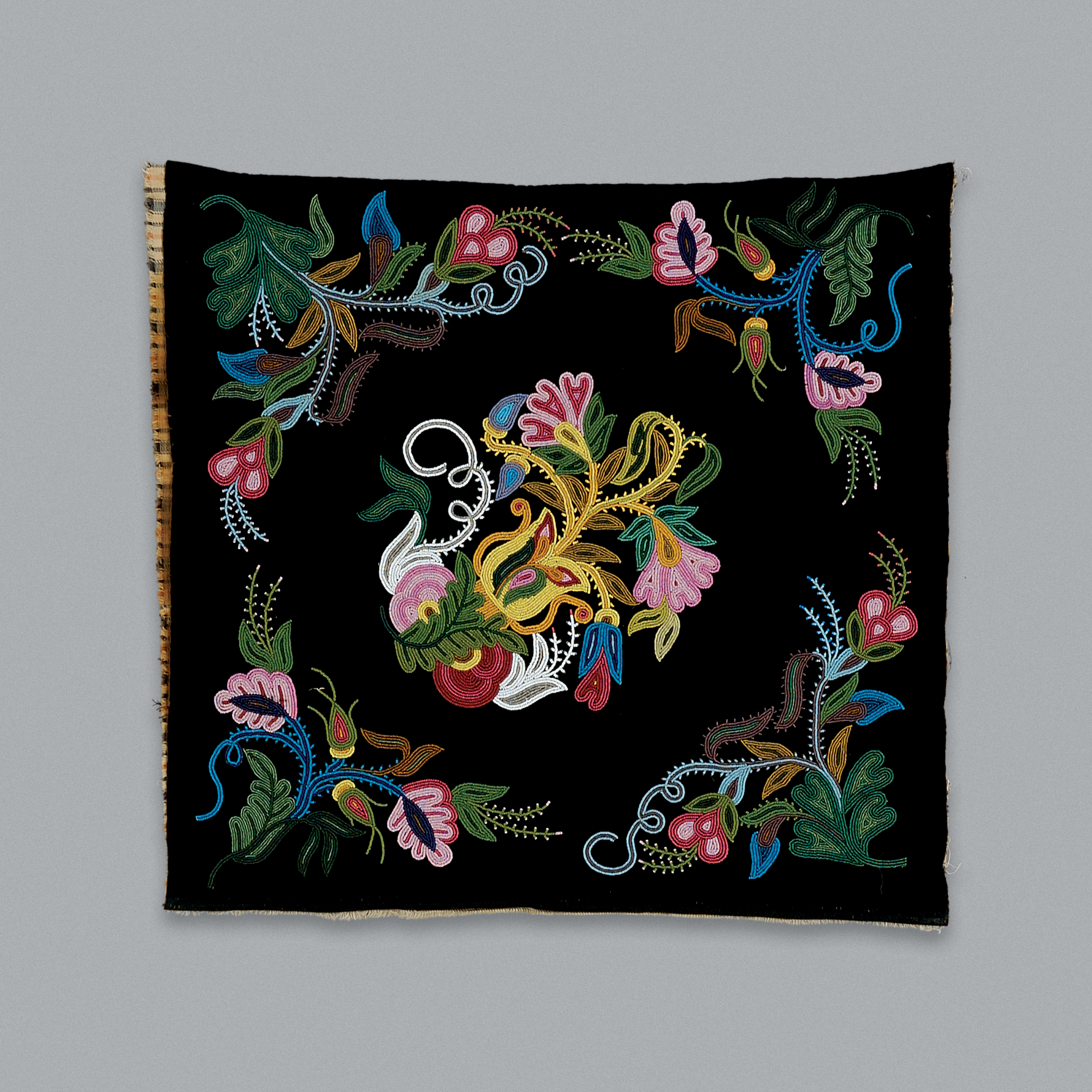 Motifs de fleurs perlés sur un tissu noir.//Flower designs beaded onto a black backing