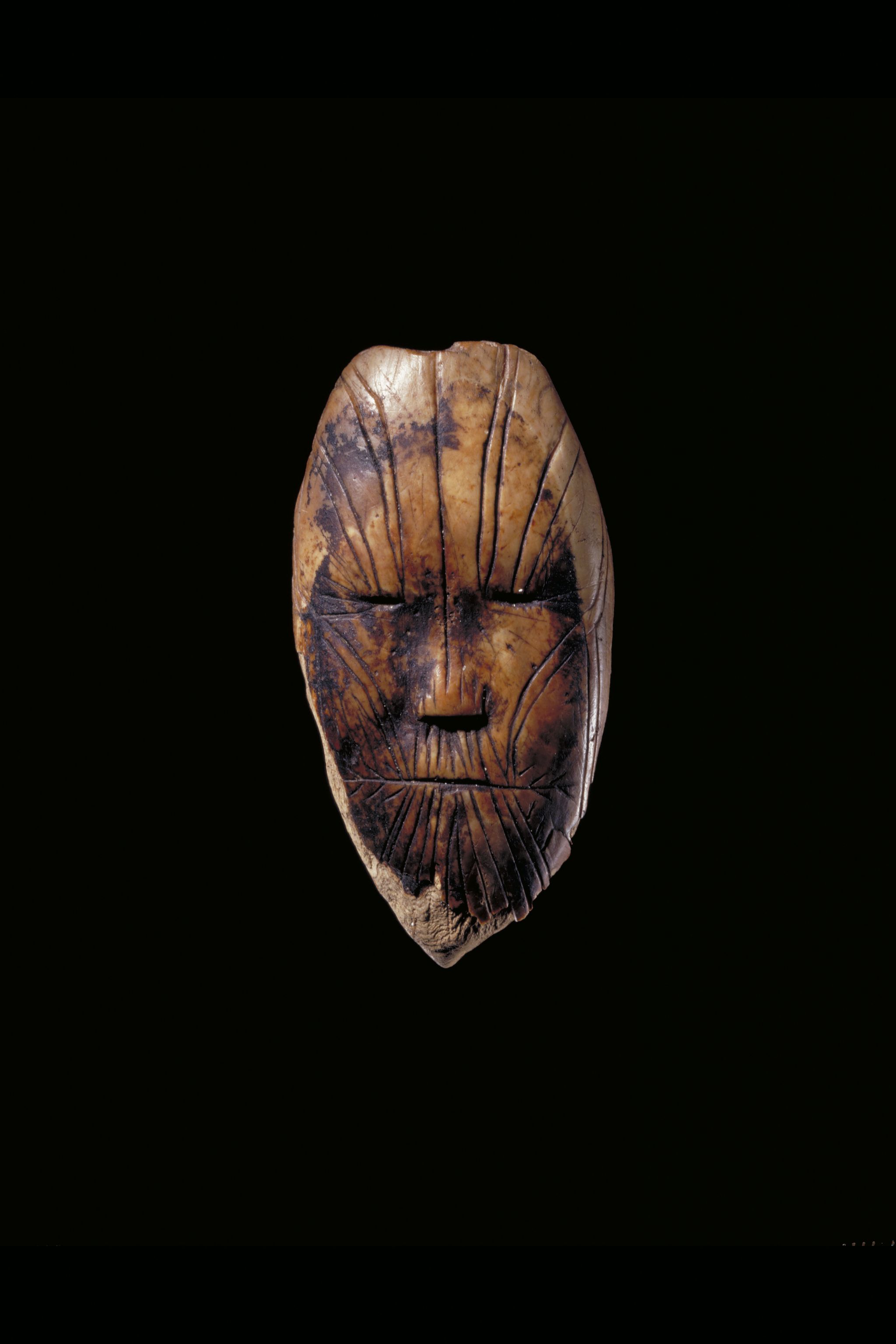 Small carving of a face with vertical lines running over it
