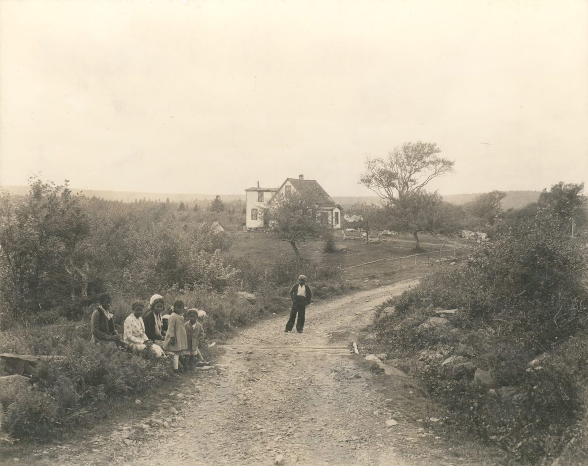 A group of children on a dirt road, with a building in the background. - Un groupe d’enfants sur un chemin de terre, avec un bâtiment à l’arrière-plan.