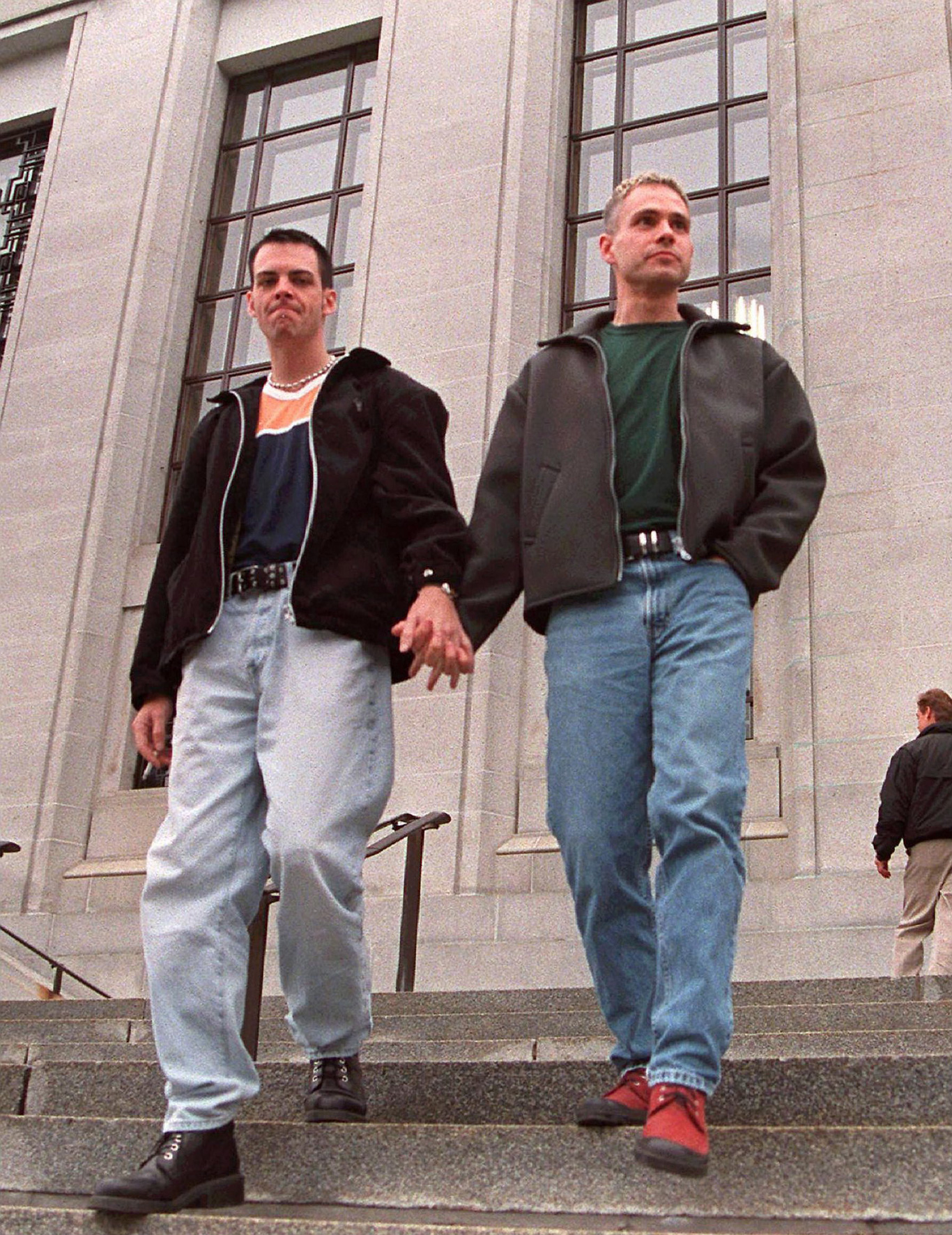 Two young men walking down outdoor steps, holding hands.