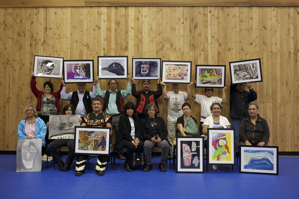 Photo en couleur d’un groupe de personnes âgées tenant des œuvres d’art encadrées.