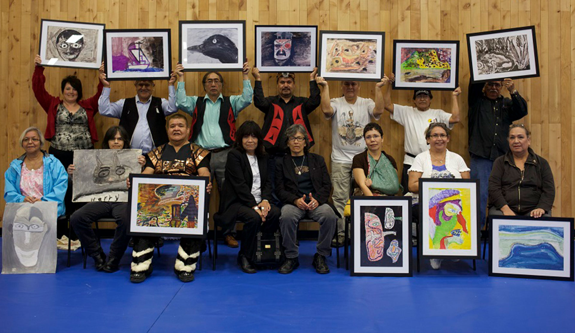 Colour photo of a group of older adults holding framed artworks.