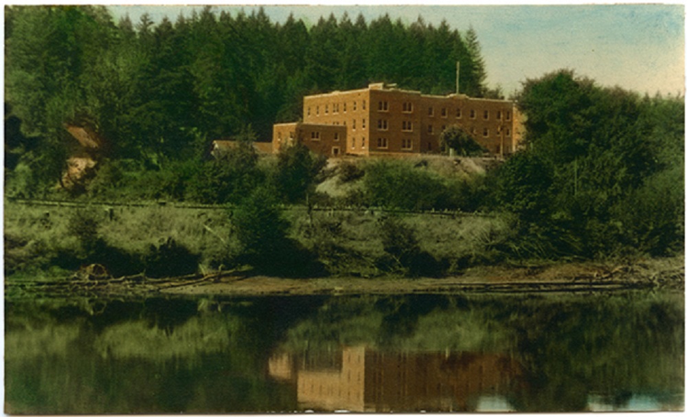 Image d’un grand bâtiment en brique rouge de trois étages surplombant l’eau.